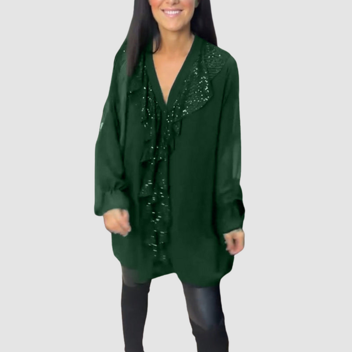 Deep green ruffled blouse with sparkling details, styled with leggings in a studio.
