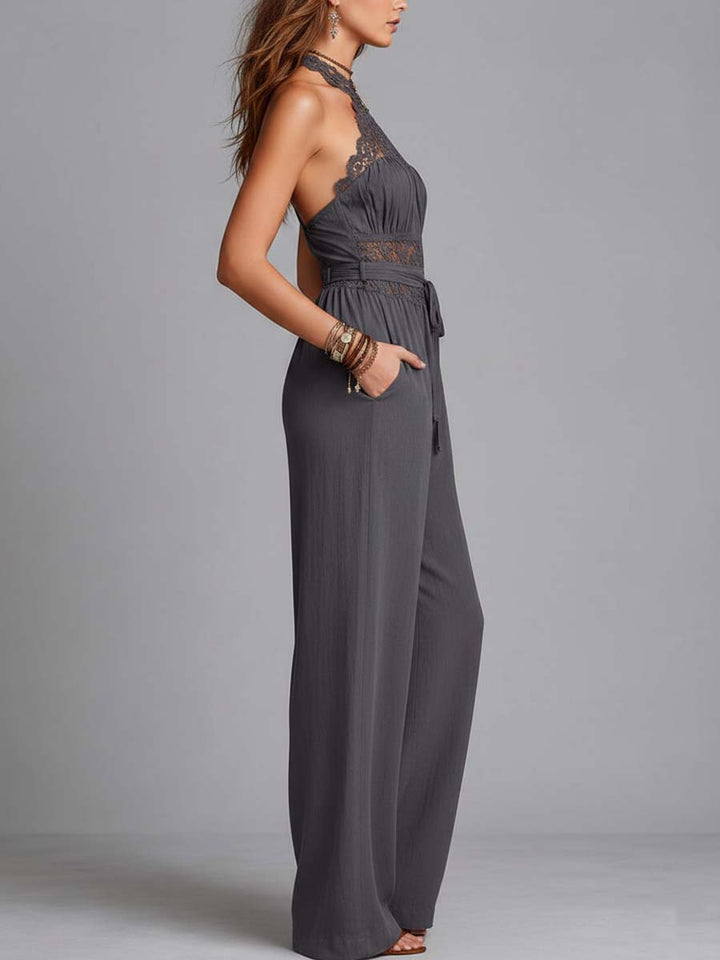 Side view of a gray halterneck jumpsuit with lace details and wide-leg pants, modeled in a studio.