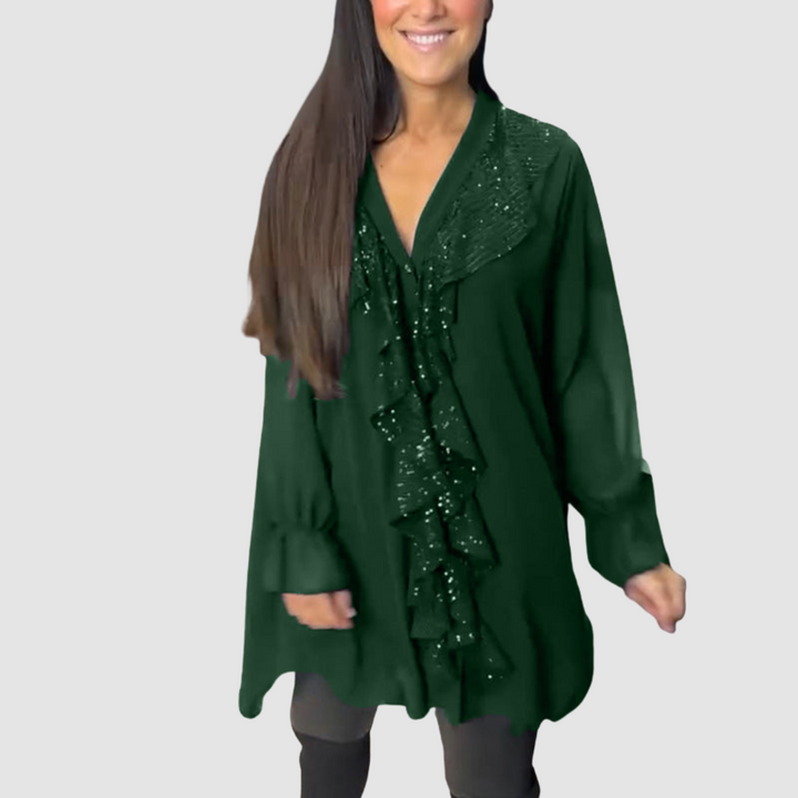Green blouse with elegant ruffled design, paired with leggings in a studio environment.