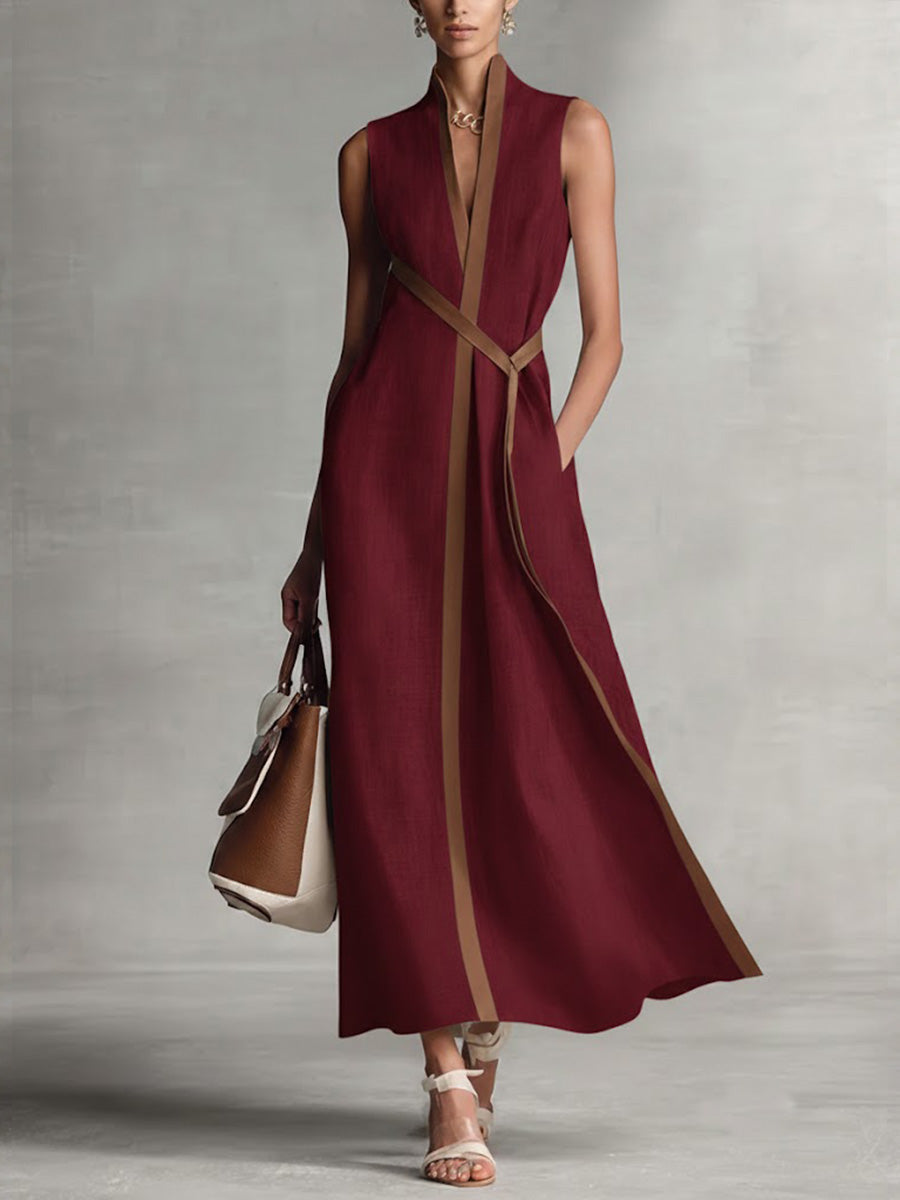 Elegant sleeveless burgundy maxi dress with brown trim, paired with a handbag and sandals in a studio setting.
