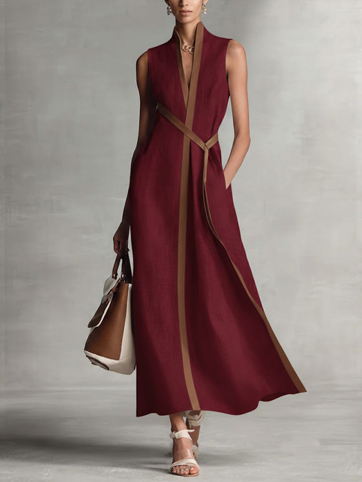 Elegant sleeveless burgundy maxi dress with brown trim, paired with a handbag and sandals in a studio setting.