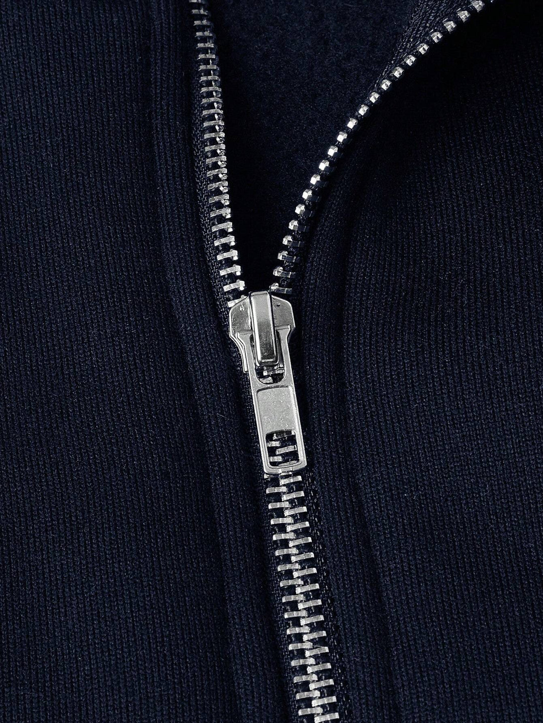 Close-up of silver zipper on a navy blue fabric, highlighting texture and detail.