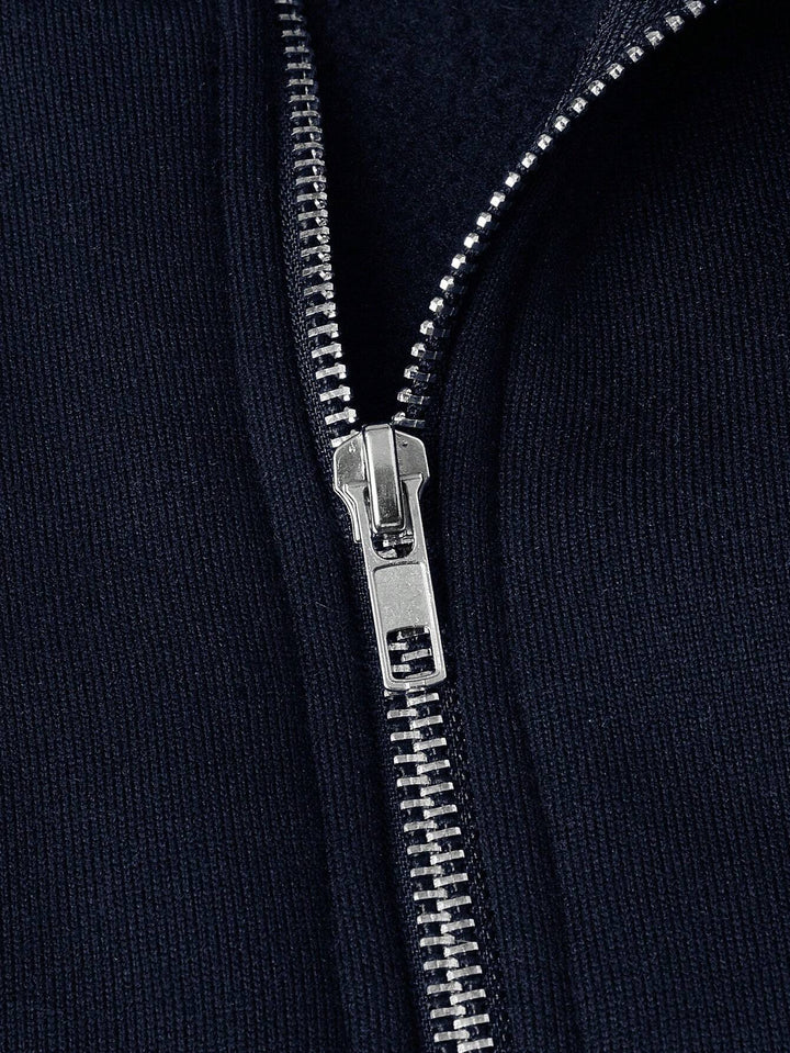 Close-up of silver zipper on a navy blue fabric, highlighting texture and detail.