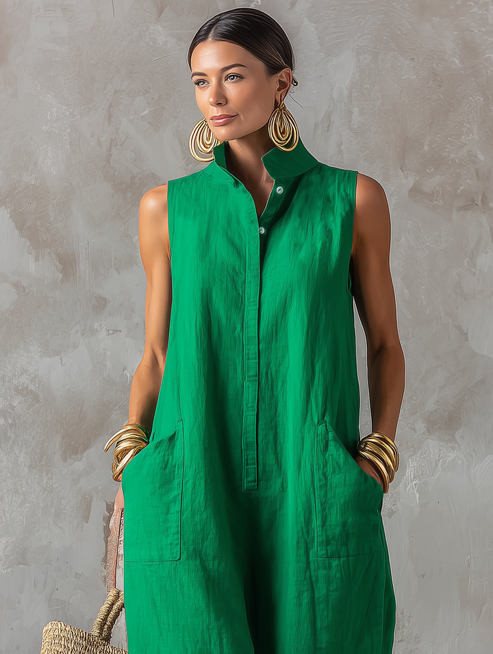 Close-up of model wearing a green sleeveless jumpsuit with button detailing, featuring gold earrings and bangles in a studio setting.