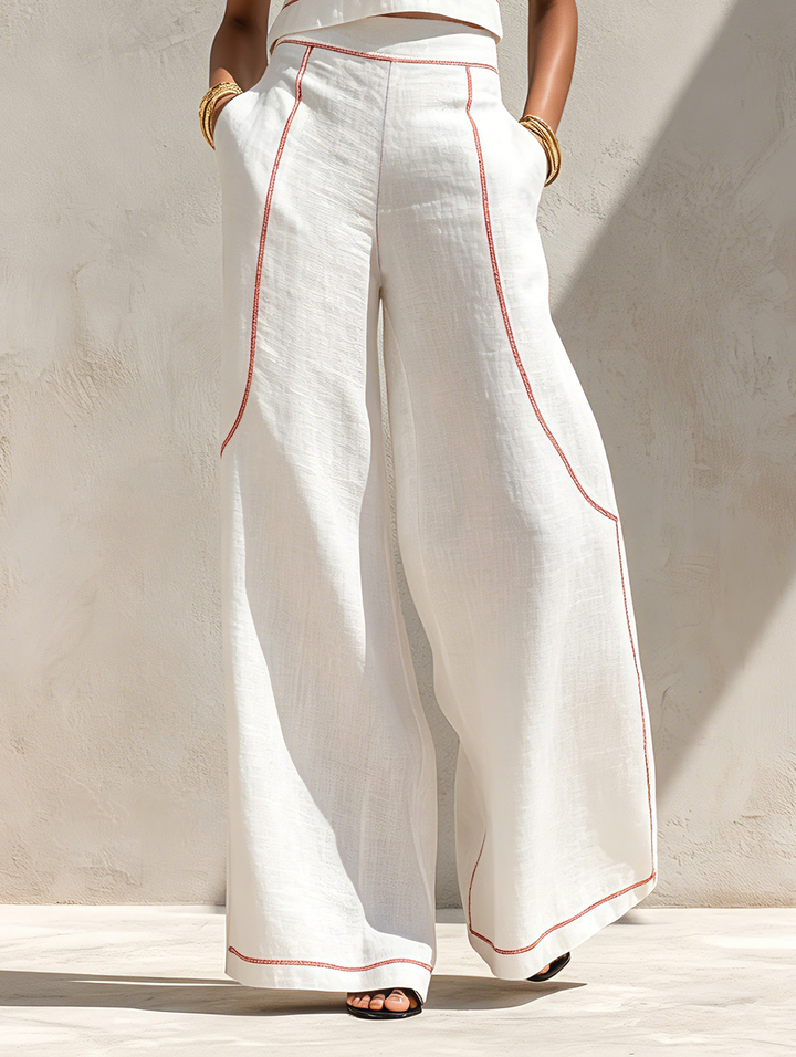 Close-up of white pants with contrast stitching, worn by woman standing outdoors with neutral background.