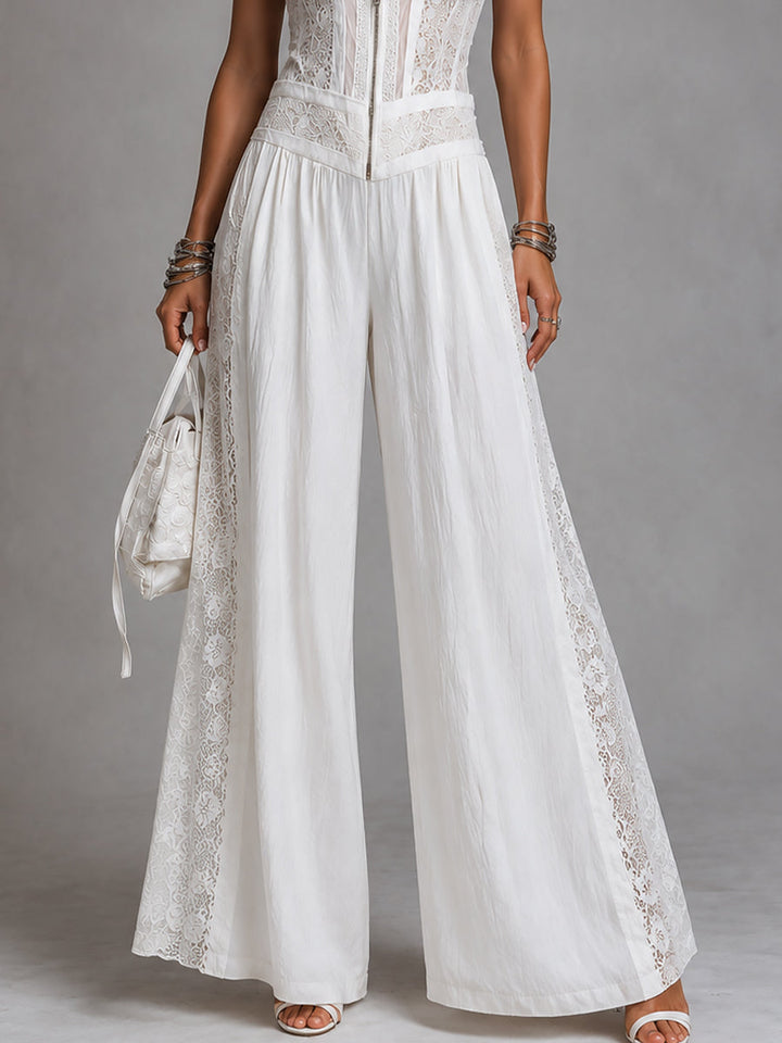 Close-up of white wide-leg jumpsuit with lace trim, studio backdrop.