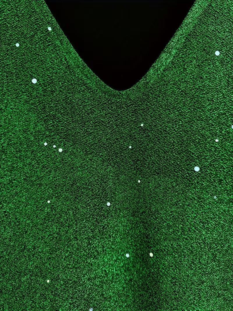 Close-up of a green dress fabric with shimmering detail and V-neckline, highlighting texture and sparkle.