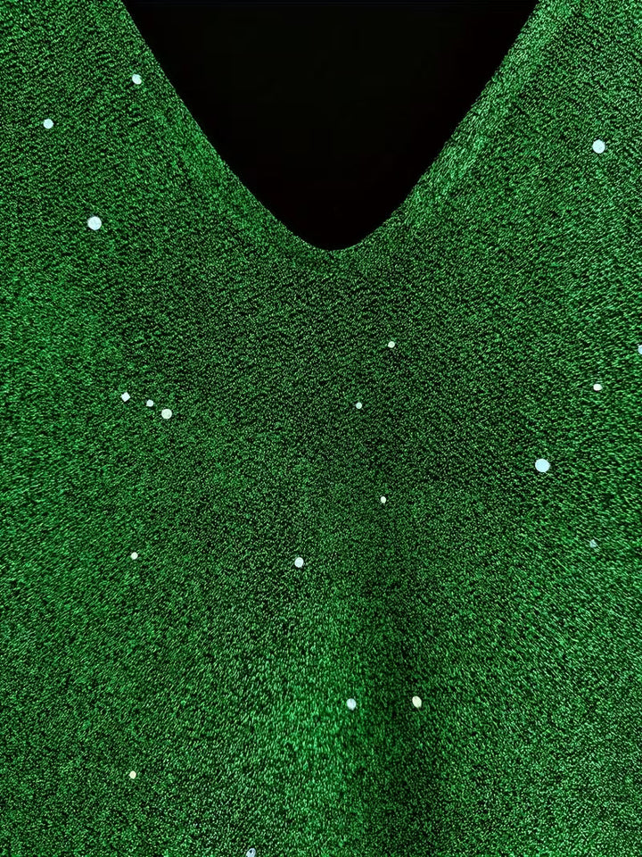 Close-up of a green dress fabric with shimmering detail and V-neckline, highlighting texture and sparkle.