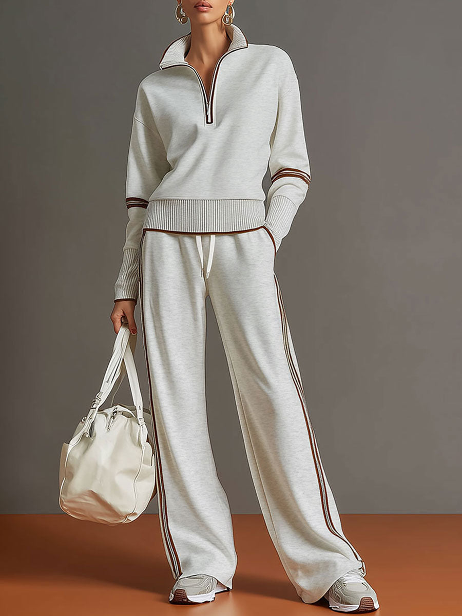 Effortless matching lounge set in light gray with contrast stripe details, paired with white sneakers and a bag in a studio setting.