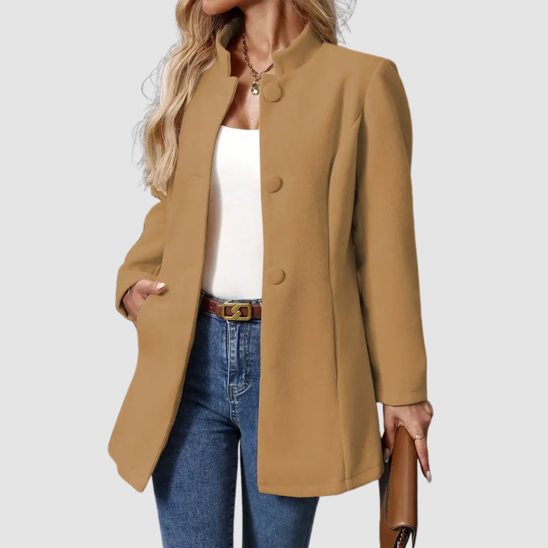 Brown jacket, large buttons, worn over white top and jeans, holding clutch, plain background.