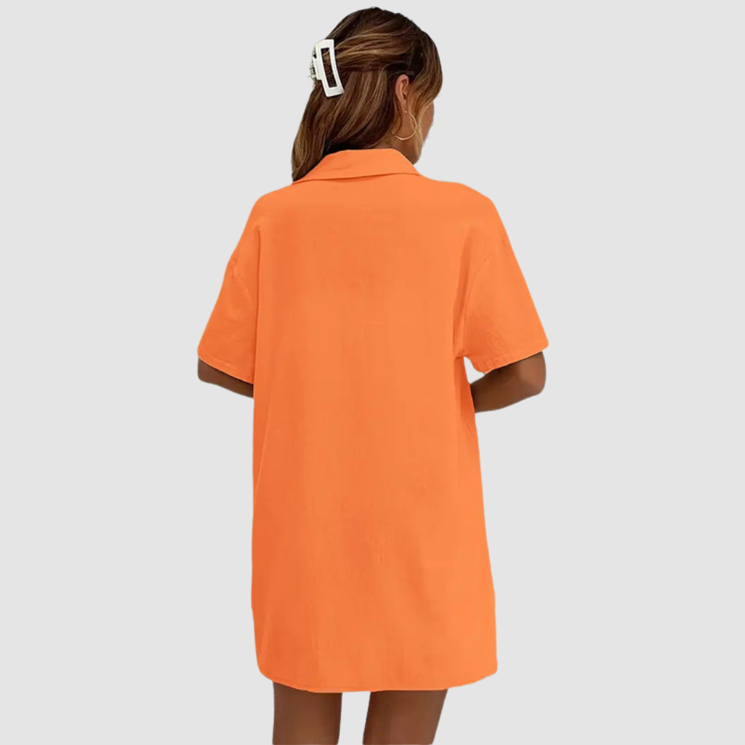 Back view of woman in orange button-up dress, hair clipped, against a studio background.