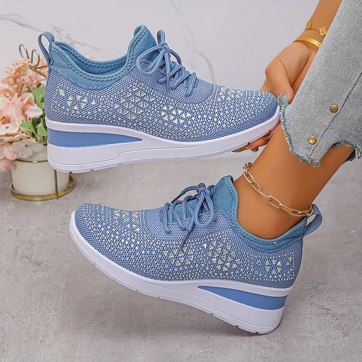 Light blue orthopedic sneakers with intricate detailing, worn in a stylish indoor space with floral accents.