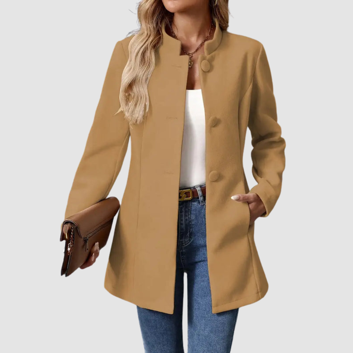 Brown jacket, large buttons, worn over white top and jeans, holding clutch, plain background.