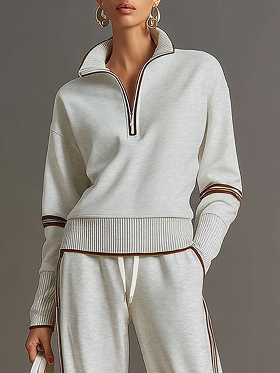 Close-up of light gray half-zip top with contrast stripes, styled in a studio setting.