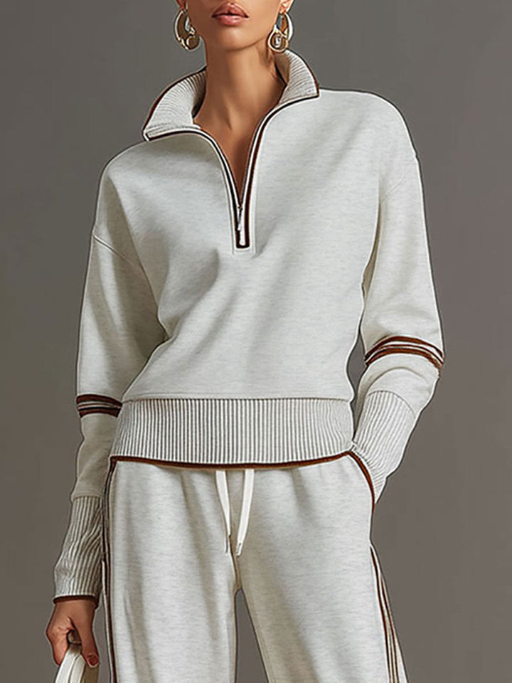 Close-up of light gray half-zip top with contrast stripes, styled in a studio setting.