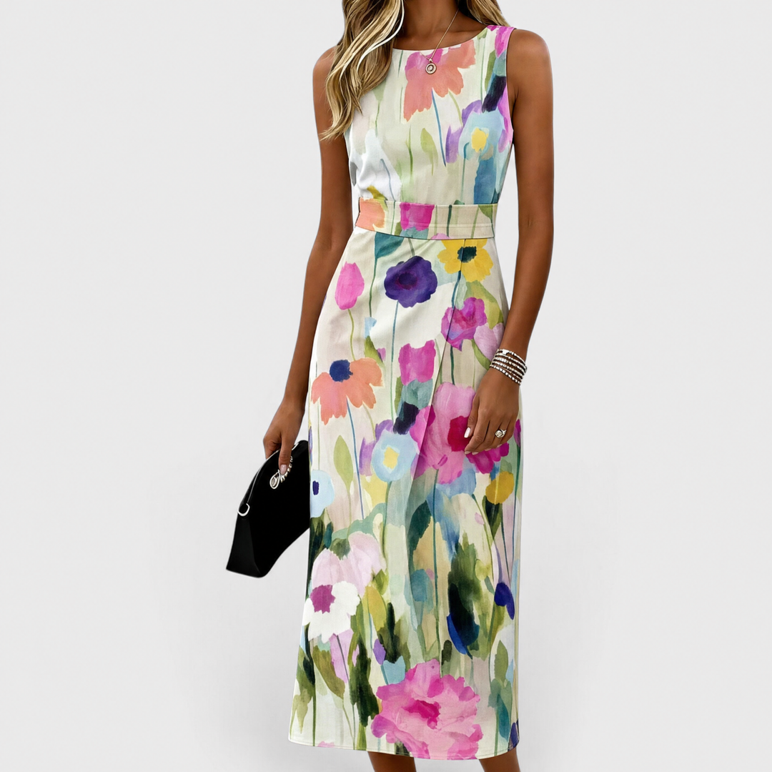 Model in floral midi dress with colorful flowers, holding black clutch in studio setting.