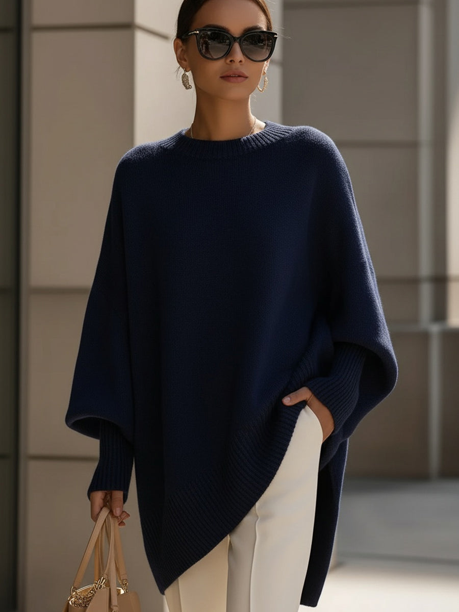 Woman in a loose navy sweater, with ribbed hem and cuffs, paired with white pants, in an urban setting.