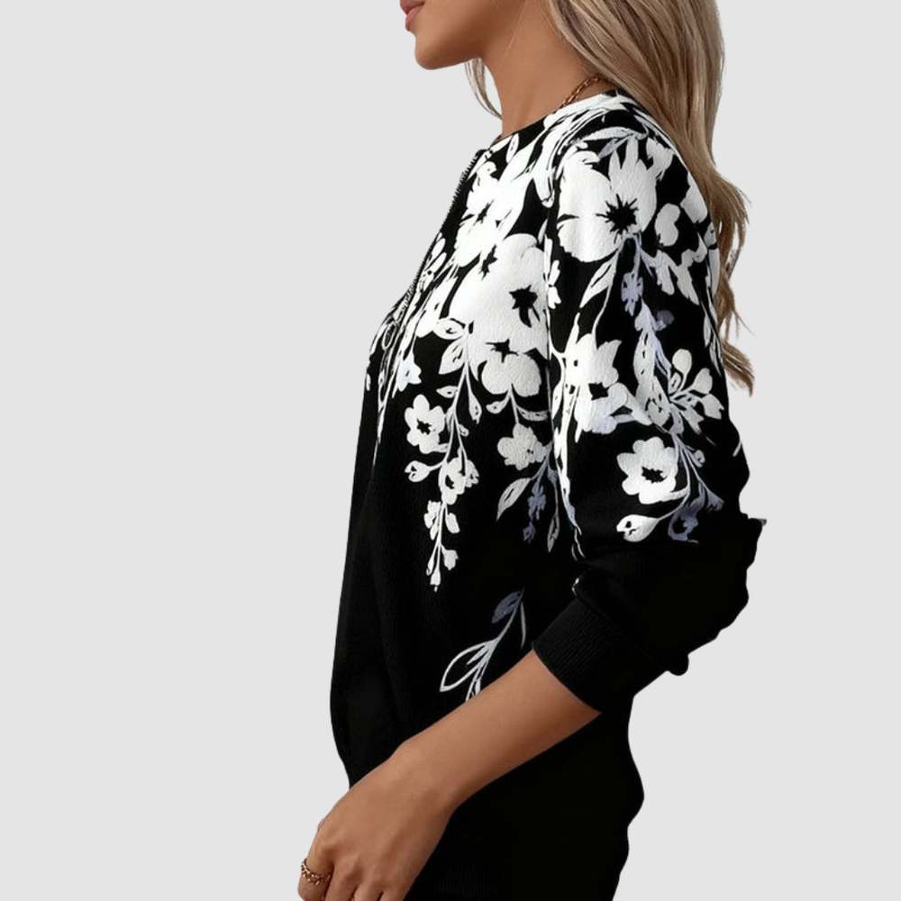 Side view of black half zip sweatshirt with white floral design, worn by model in studio setting.