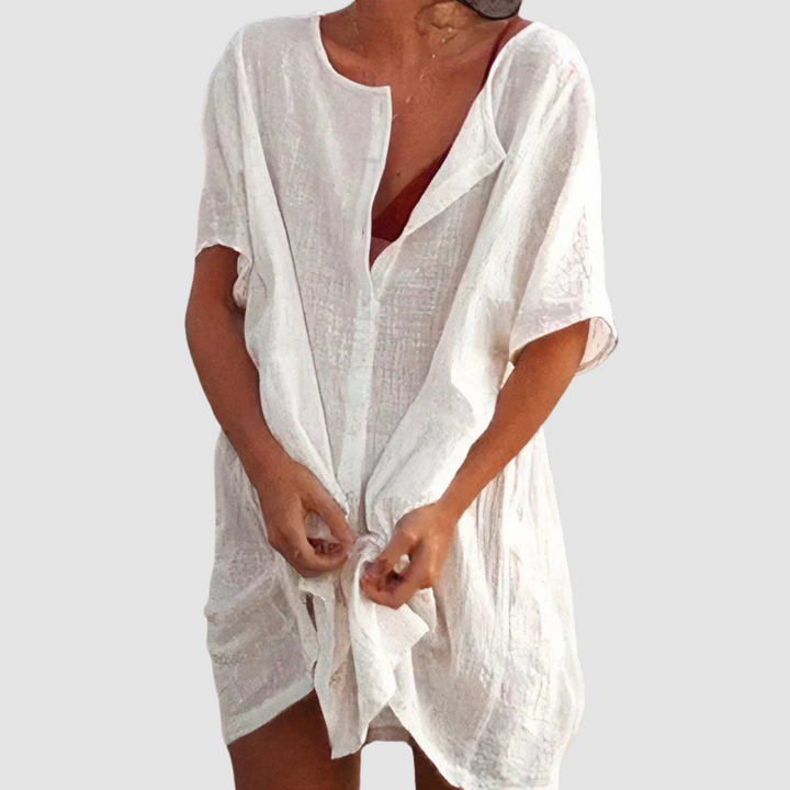 White loose fit dress with short sleeves and textured fabric, worn by person with untied front, studio background.