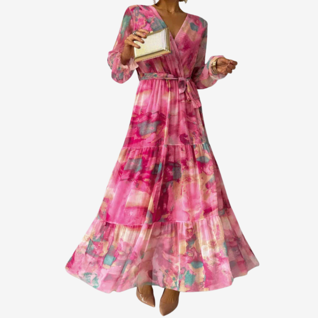 Elegant pink dress with abstract patterns, long sleeves and flowing skirt. Model holding a gold clutch, studio setting.