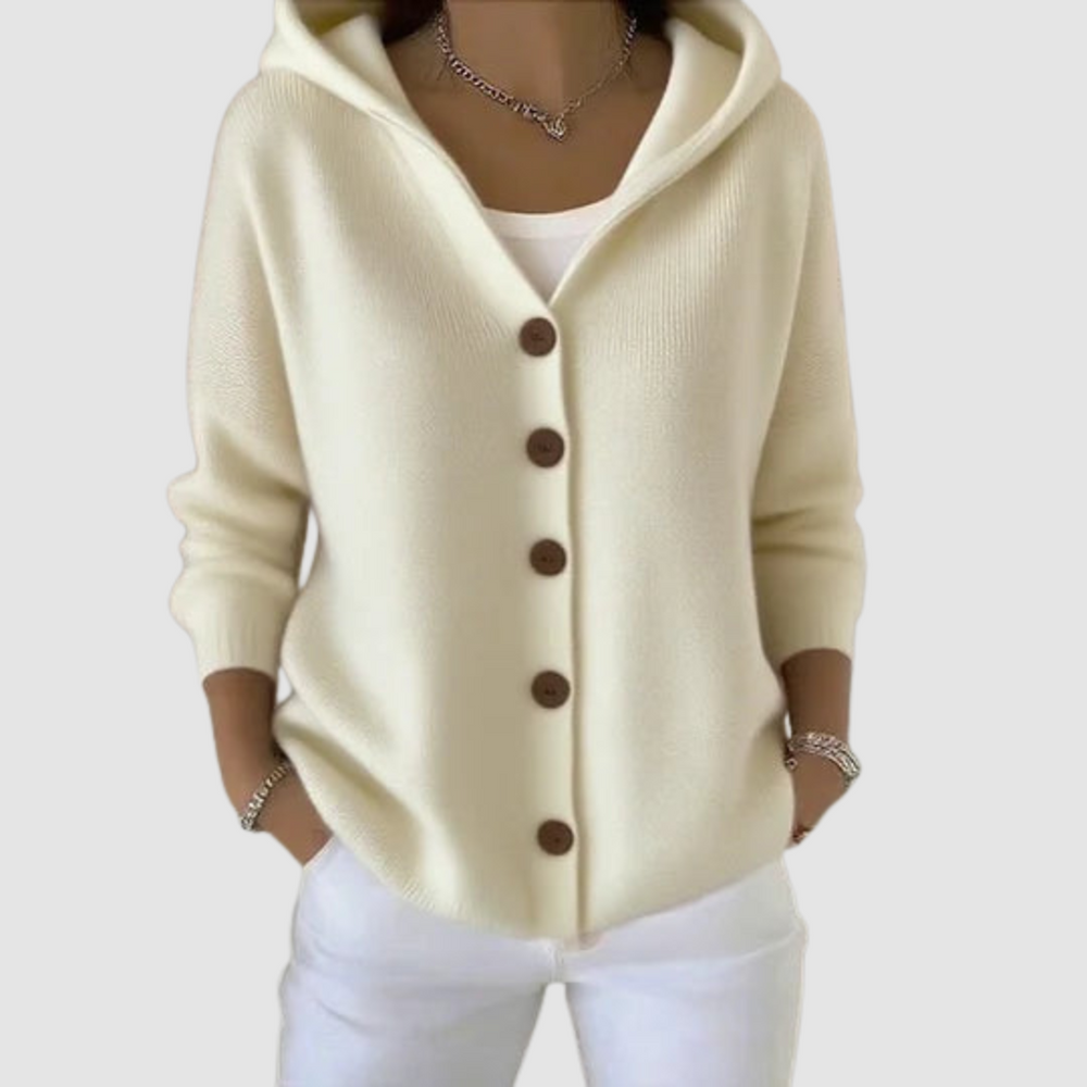 Cream hooded cardigan with brown buttons, worn over a white top, against a light gray background.