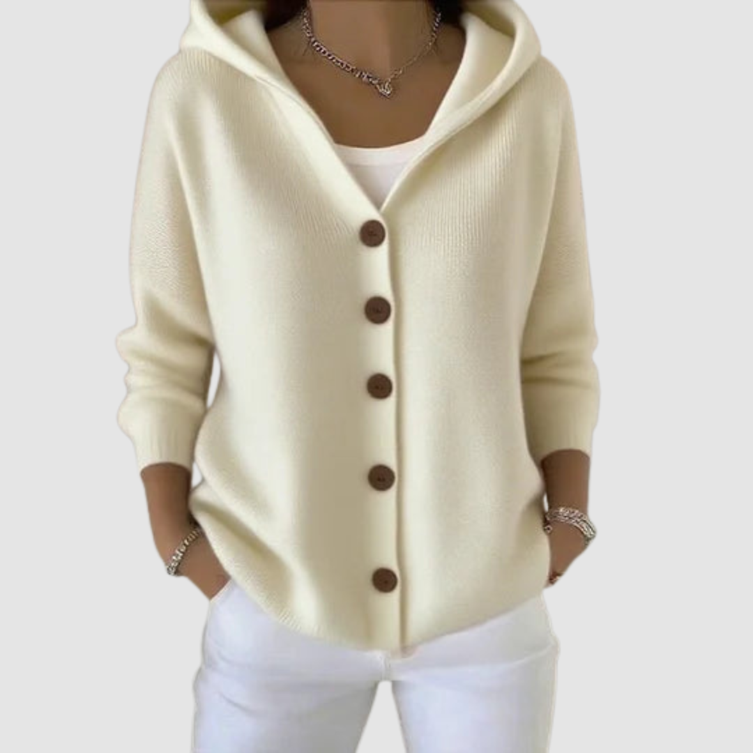 Cream hooded cardigan with brown buttons, worn over a white top, against a light gray background.