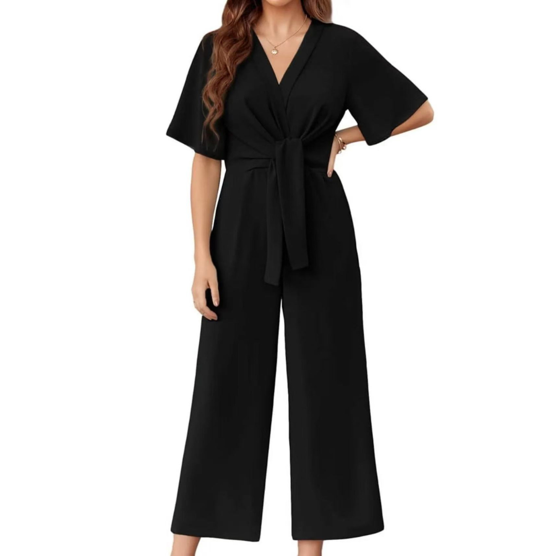 Black elegant jumpsuit with short sleeves and a tie waist on a woman, studio background.