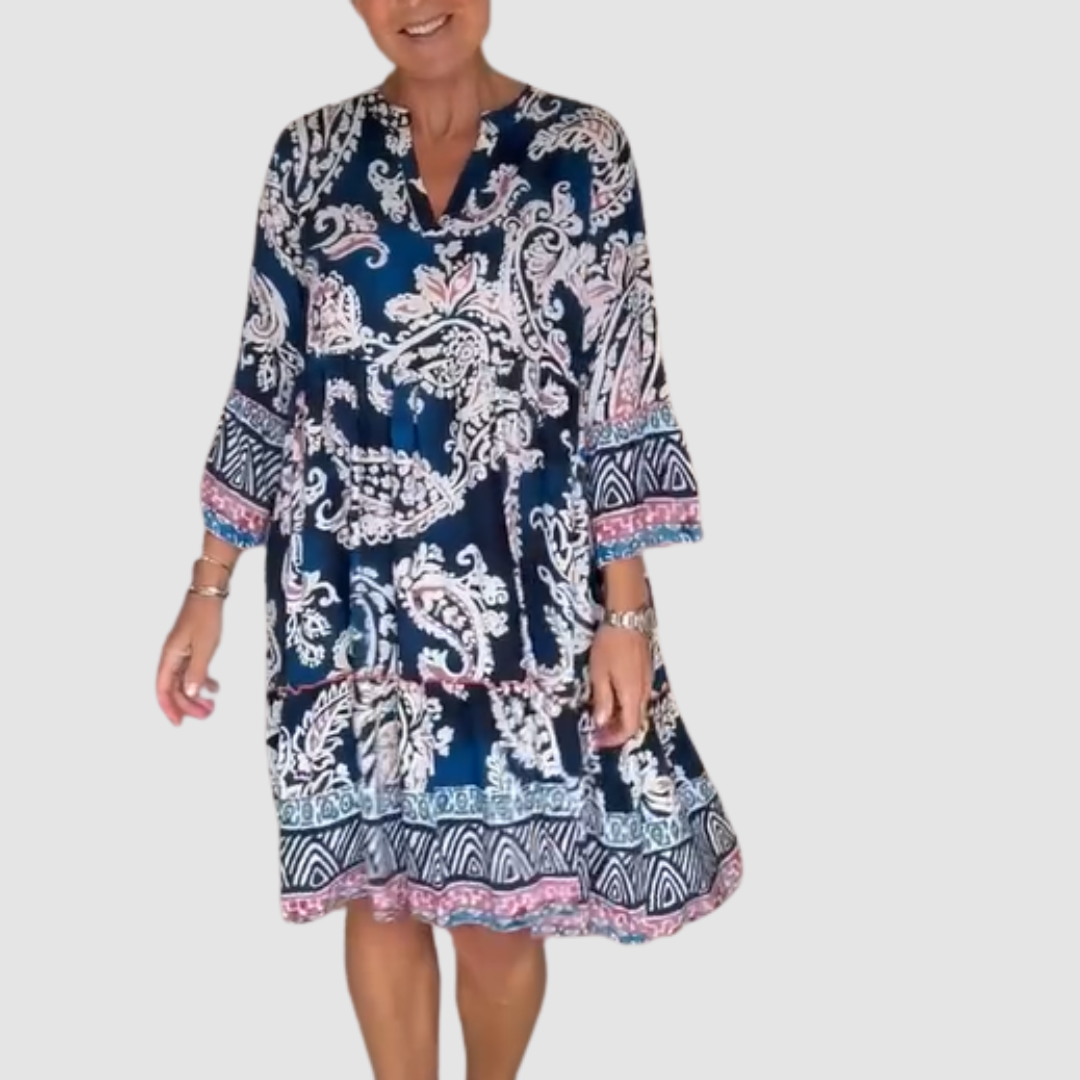 Blue, pink paisley V-neck dress with 3/4 sleeves in a studio setting.