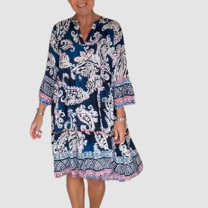 Blue, pink paisley V-neck dress with 3/4 sleeves in a studio setting.