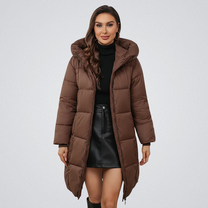 Woman in a brown puffer coat with hood, styled with a black turtleneck and black skirt, on a white background.