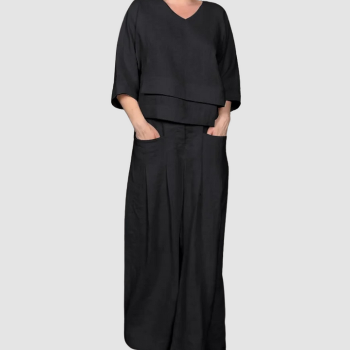 Black relaxed 2-piece set with V-neck top and wide-leg pants featuring pockets, studio background.