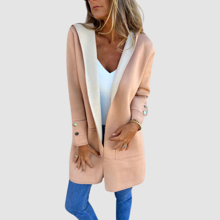 Blush and gray colorblock hooded jacket worn over white top and jeans in a studio setting.