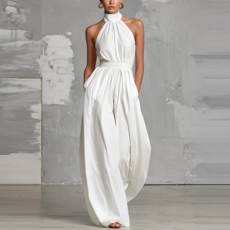White halter-neck jumpsuit with wide legs in a minimalist studio setting.