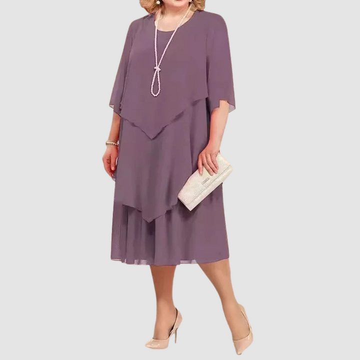 Purple chiffon midi dress with layered design, worn with pearl necklace and beige clutch against white background.