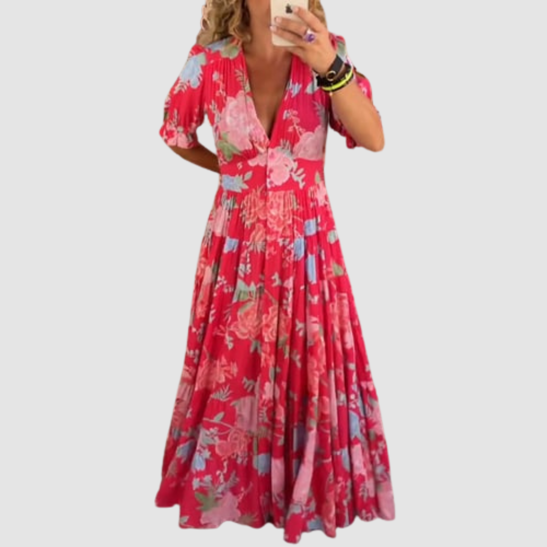 Red floral long dress with short sleeves and a flowy design, modeled indoors with a neutral background.