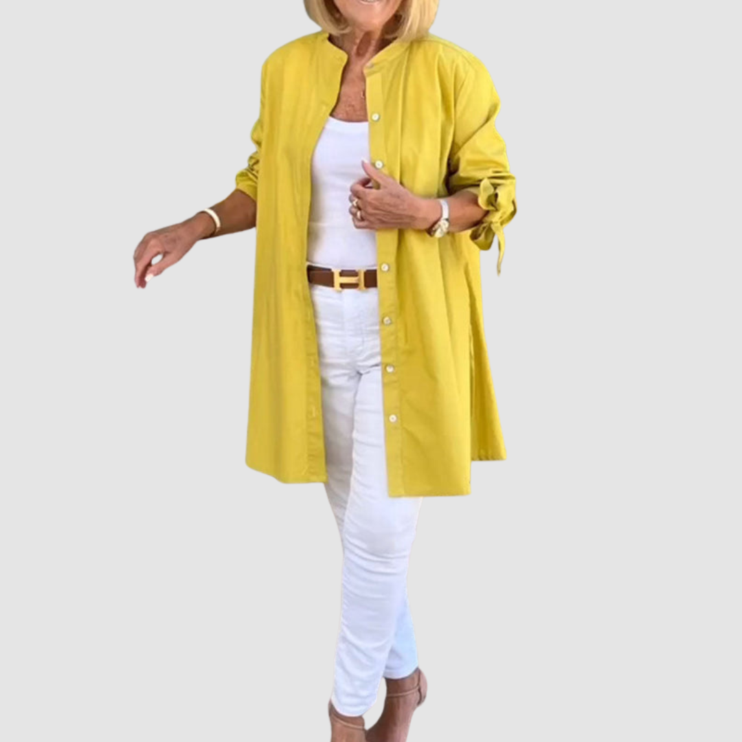 Person in a yellow long-sleeve shirt over a white outfit, posing on a light gray backdrop.