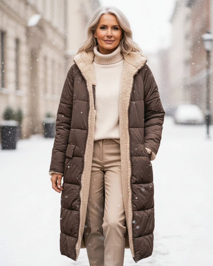 Woman in brown winter coat with fleece lining, walking in a snowy urban street.