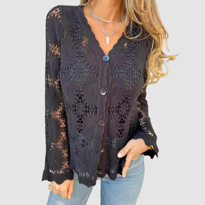 Black lace V-neck cardigan with floral designs, paired with blue jeans. Studio background.