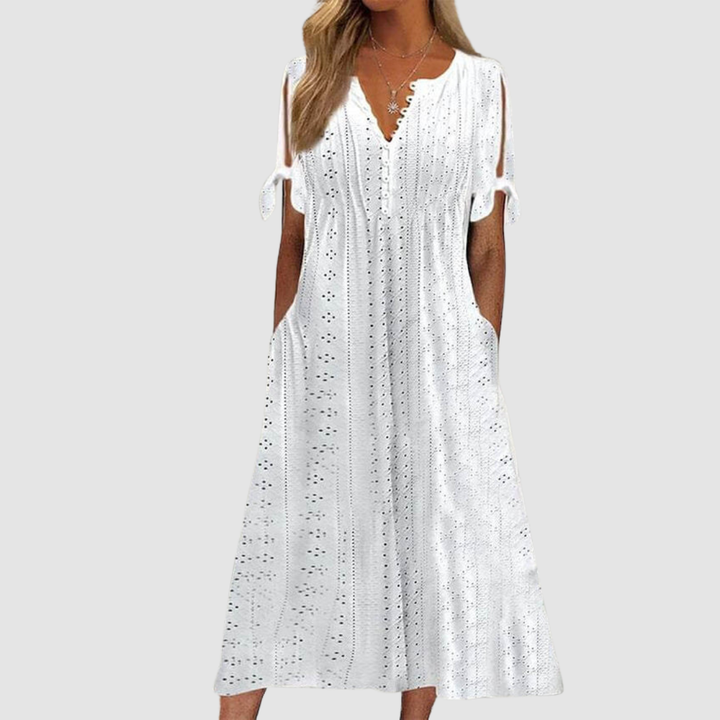 White elegant casual dress with eyelet details and tie sleeves, modeled in a studio setting.