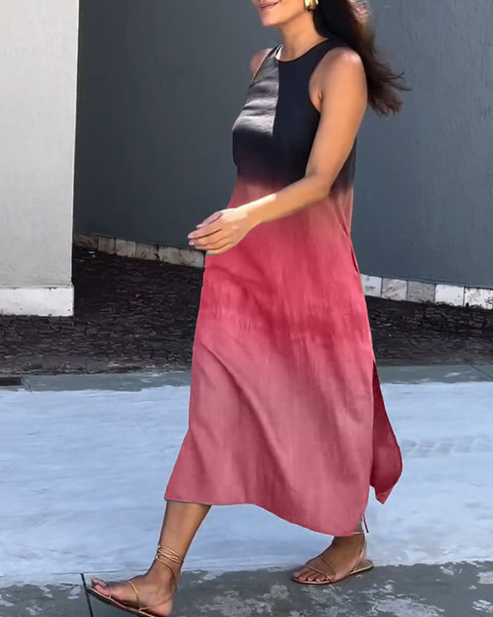Model walking in a sleeveless ombre black to red dress along a stone path outdoors.