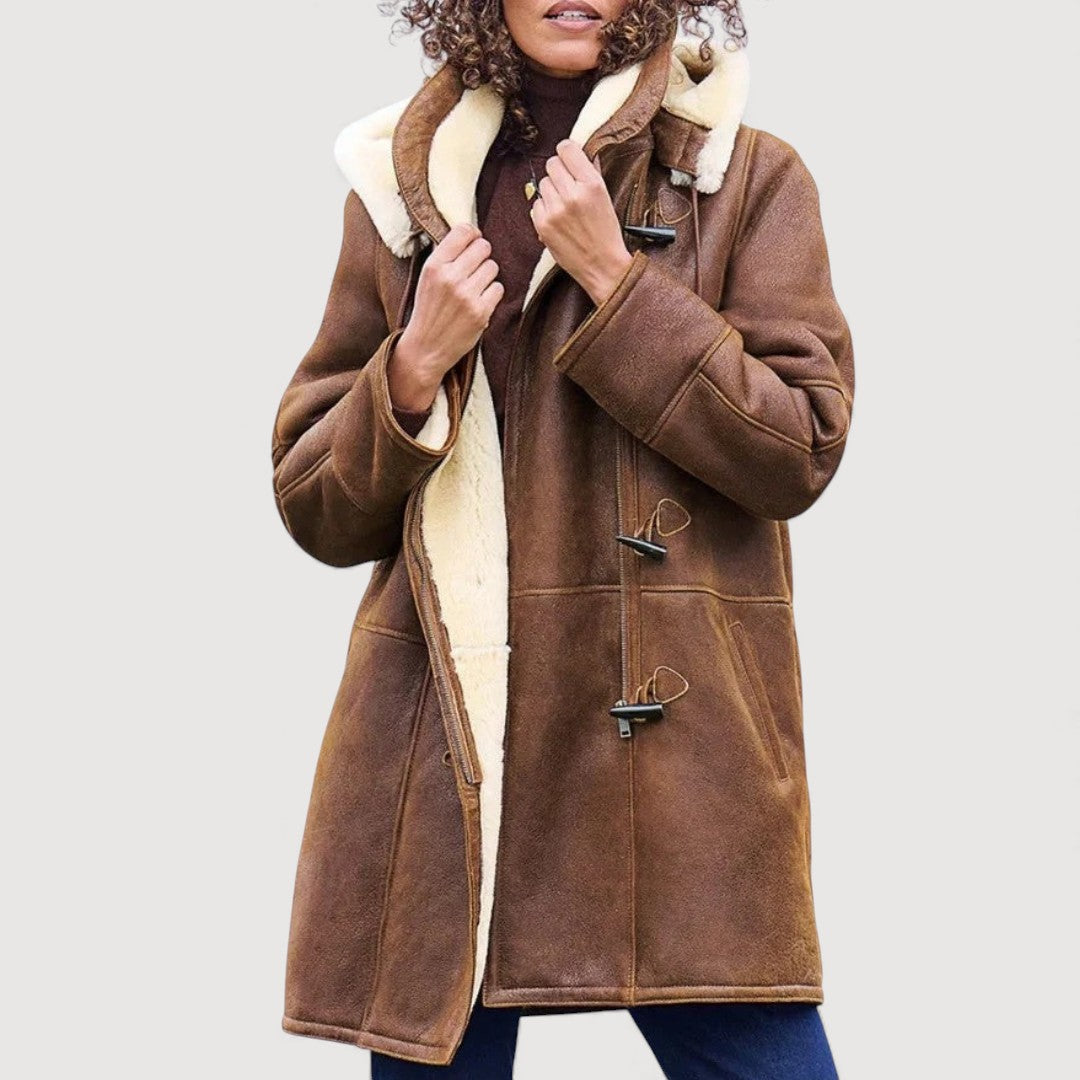 Brown coat with toggle closures and cream lining worn by a person. Plain light background.