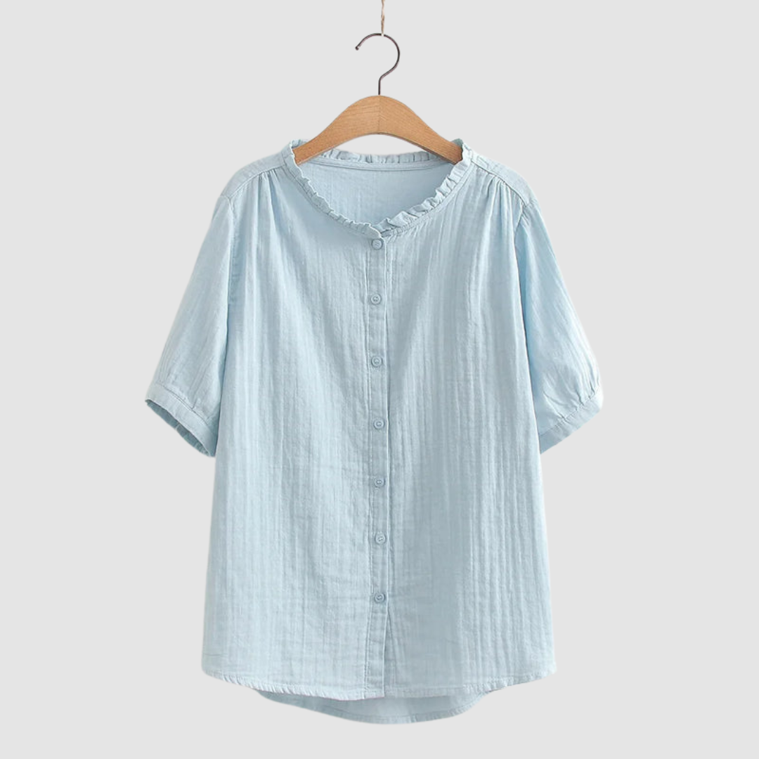 Light blue button-up shirt with ruffled collar on wooden hanger, studio background.
