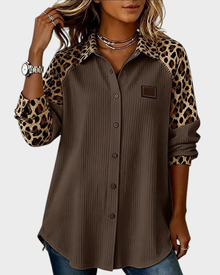 Leopard print button-down shirt in brown with brown buttons. Patterned collar and sleeves. Worn by model in a studio.