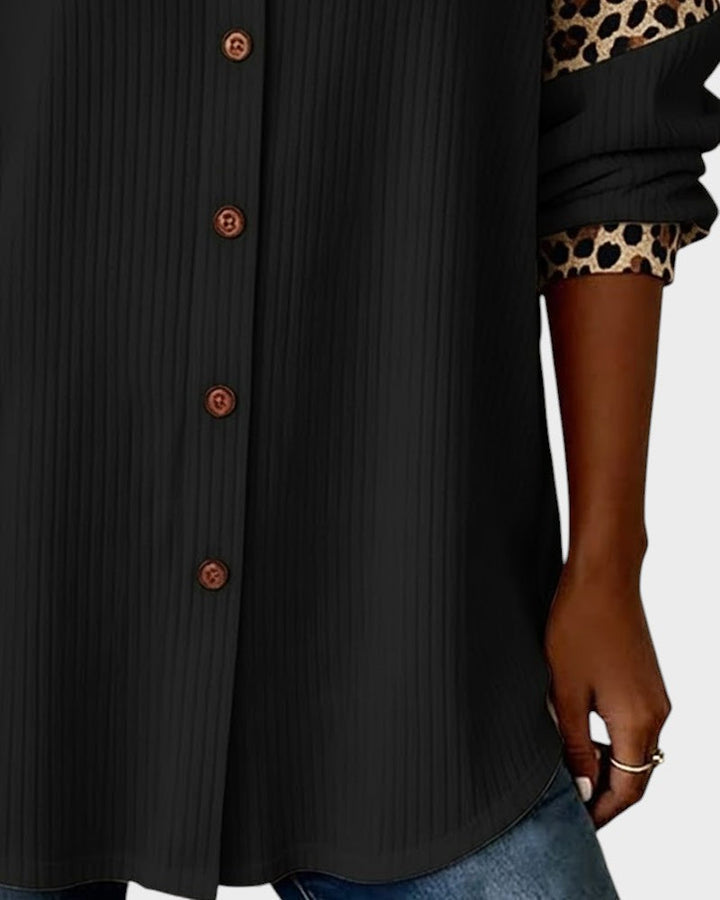 Close-up of leopard print button-down shirt bottom. Black shirt with brown buttons and patterned cuffs in a studio.