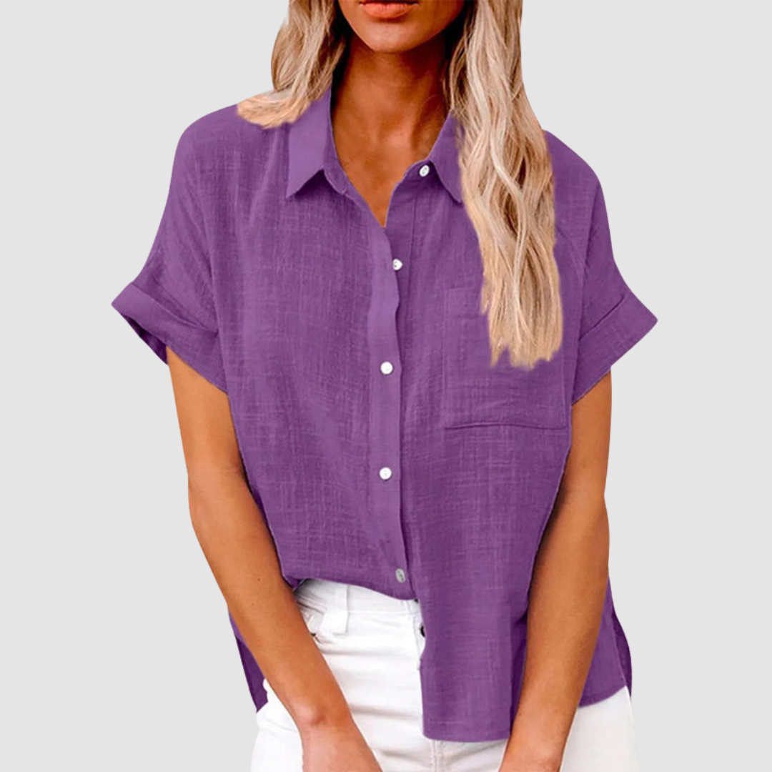 Purple casual blouse with short sleeves and front buttons, worn in white jeans. Studio background.