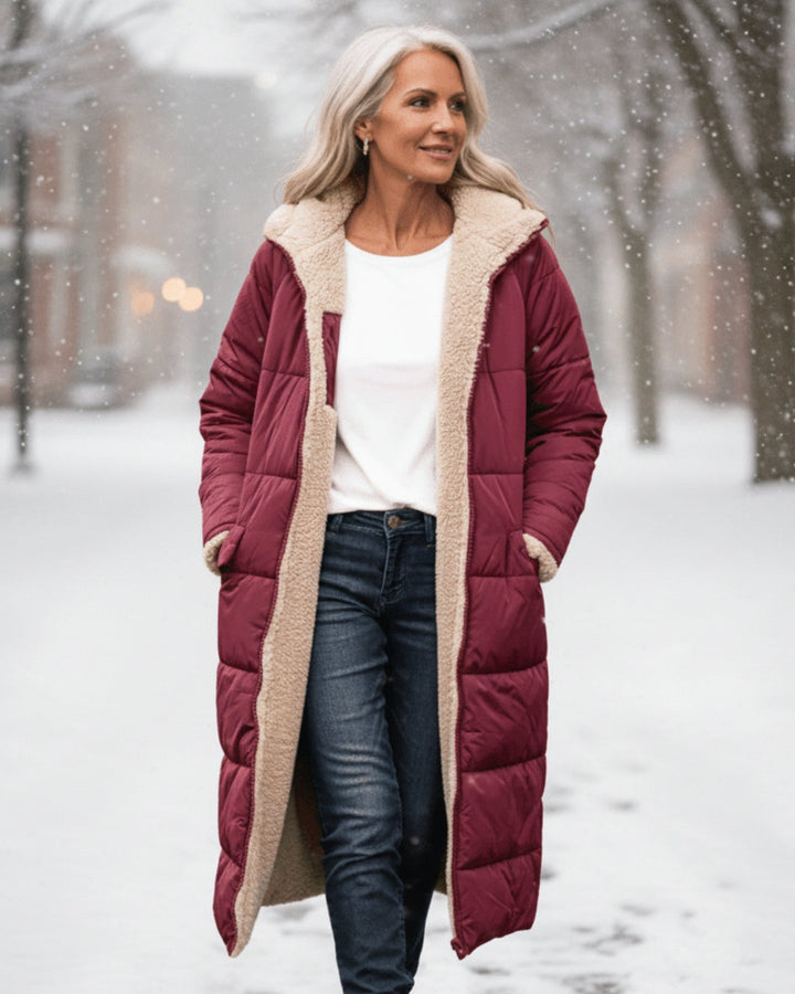 Woman in red winter coat with fleece lining, walking in a snowy urban area.