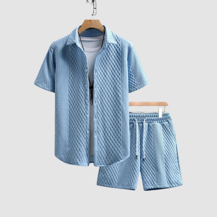 Light blue short-sleeve shirt and shorts on hangers, with a white T-shirt underneath, against a light gray background.