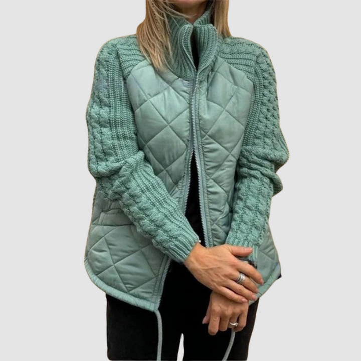 Turquoise quilted jacket with knit sleeves, worn by a person in casual setting.