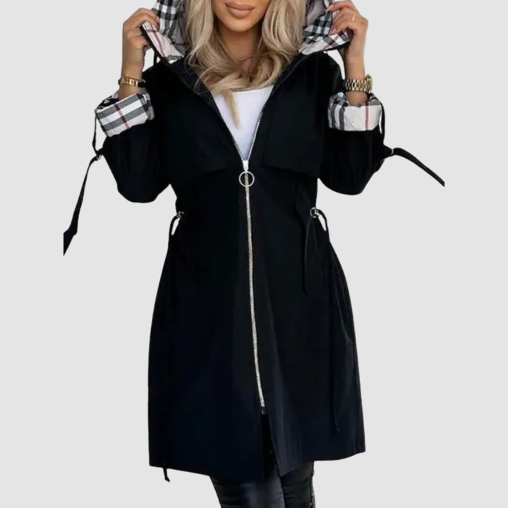 Black waterproof zip coat with plaid-lined hood and cuffs, worn over a white top and leggings, against a white background.