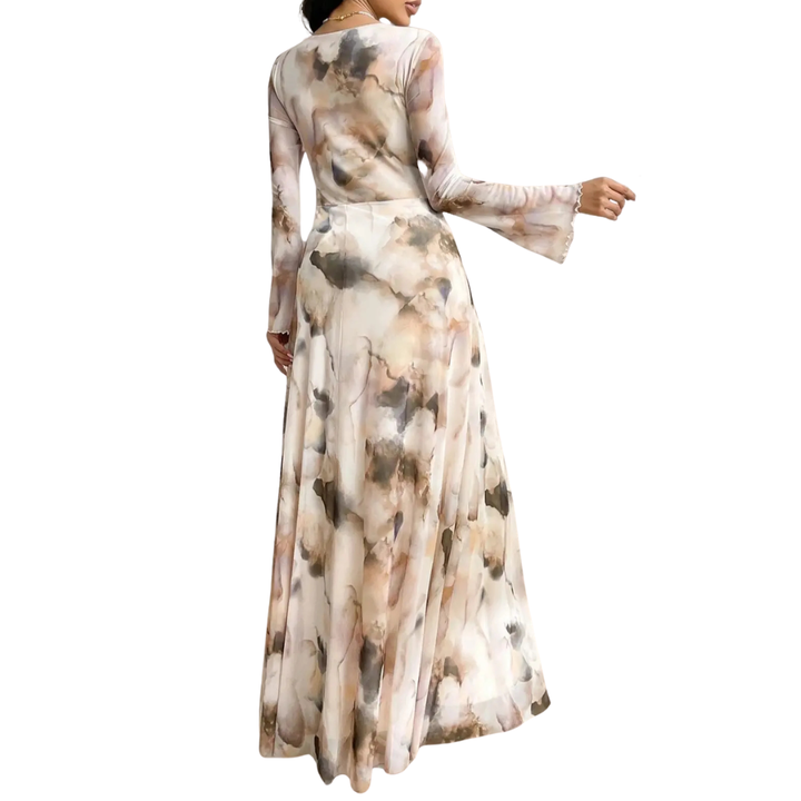 Back view of a flowing long dress with an abstract watercolor pattern, long sleeves, set against a plain studio background.